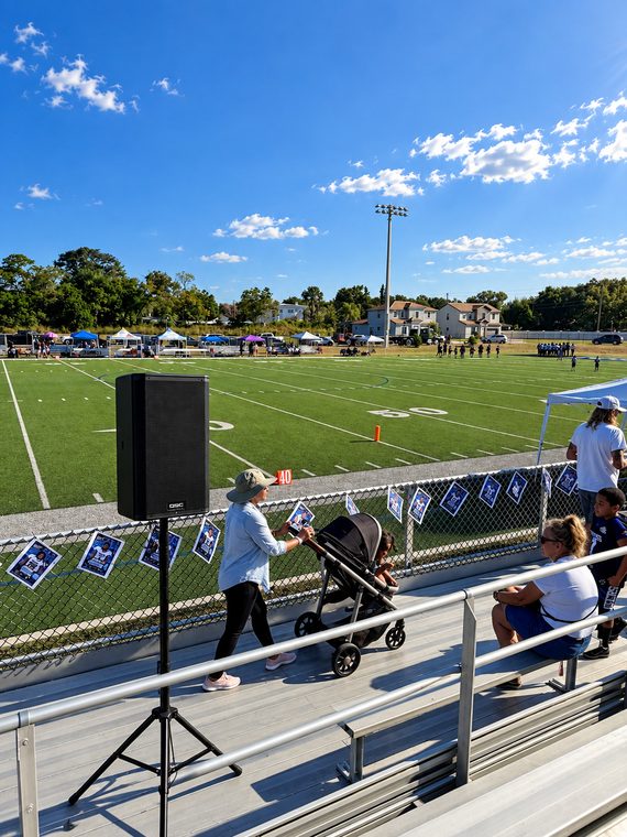 Tripod-mounted speaker providing coverage across stadium seating and a sports field