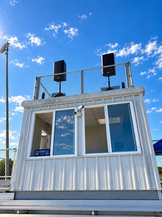 A pair of speakers elevated above the press box for broad field and bleacher coverage.
