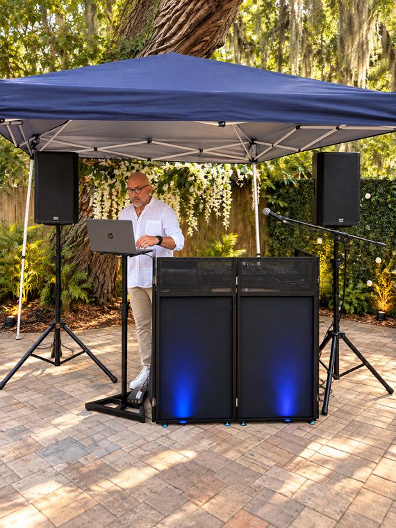 DJ facade and speaker system prepared beneath a canopy for a garden event