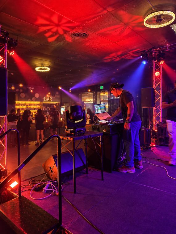 DJ working on a club stage with moving lights and professional sound equipment