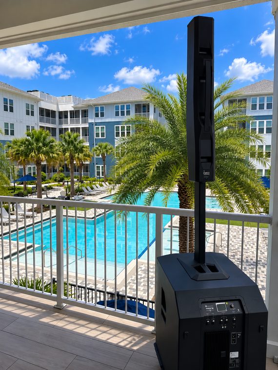 Column-array sound system and subwoofer above a pool courtyard