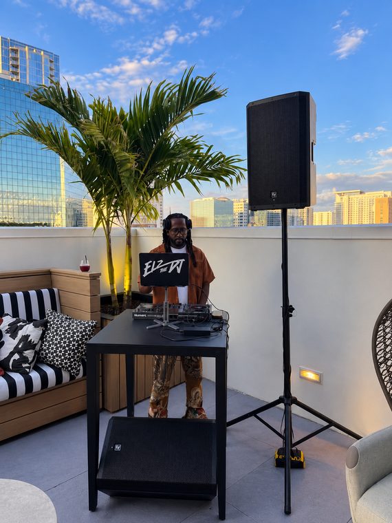 A compact DJ controller, speaker and floor monitor on a rooftop overlooking the city.