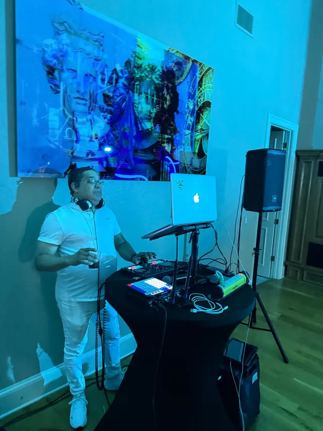 DJ controller, laptop and speaker in a blue-lit event room